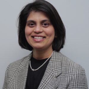 Head and shoulders shot of a young Indian businesswomen, she has a short bob and a smile looking towards the camera.