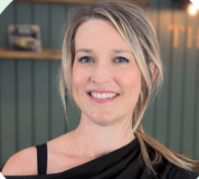 Headshot photograph of a smiling woman with long hair in a black dress